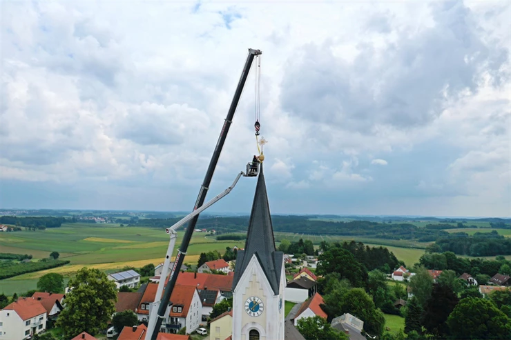 Dachdecker repariert Kirchendach in Attenkirchen mit Kran und Hebebühne. 